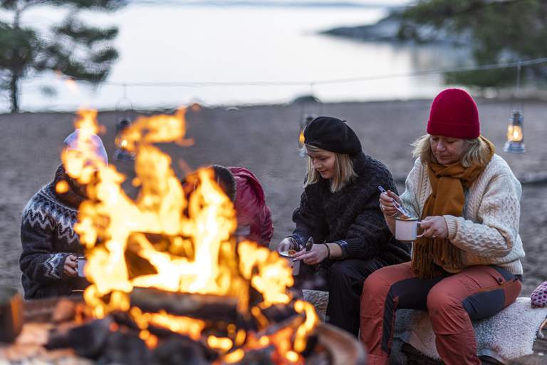 Winter in the archipelago. A family is having an outdoor dinner by a campfire on Bjjörnö.