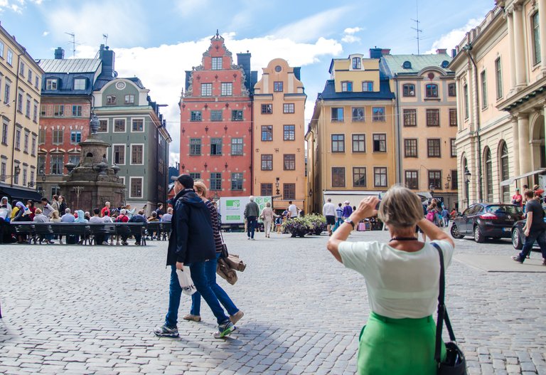 People in a square with multi-colored old houses.