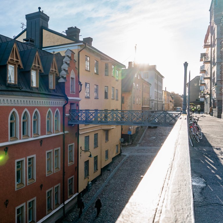 A steep , sunny cobble-stoned street lined with historic colorful buildings