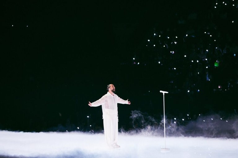 the artist Slimane on stage, wearing white