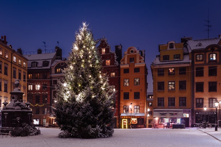 Winter in Stockholm. A snowy evening in Old Town. Pictured is Stortorget, a square in the middle of the district. Evening. A Christmas tree with glowing lights.