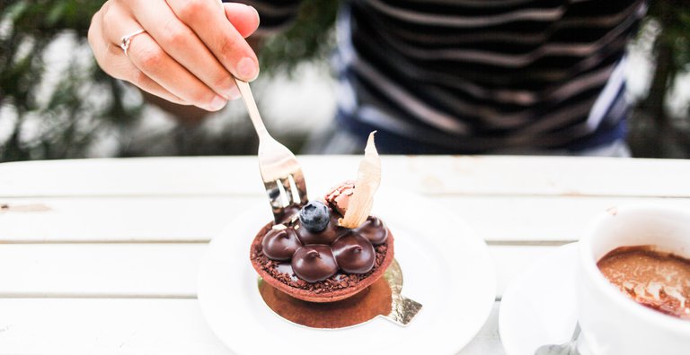 A hand, holding a fork, is cutting into a chocolate pastry at Petite France, a bakery at Kungsholmen.