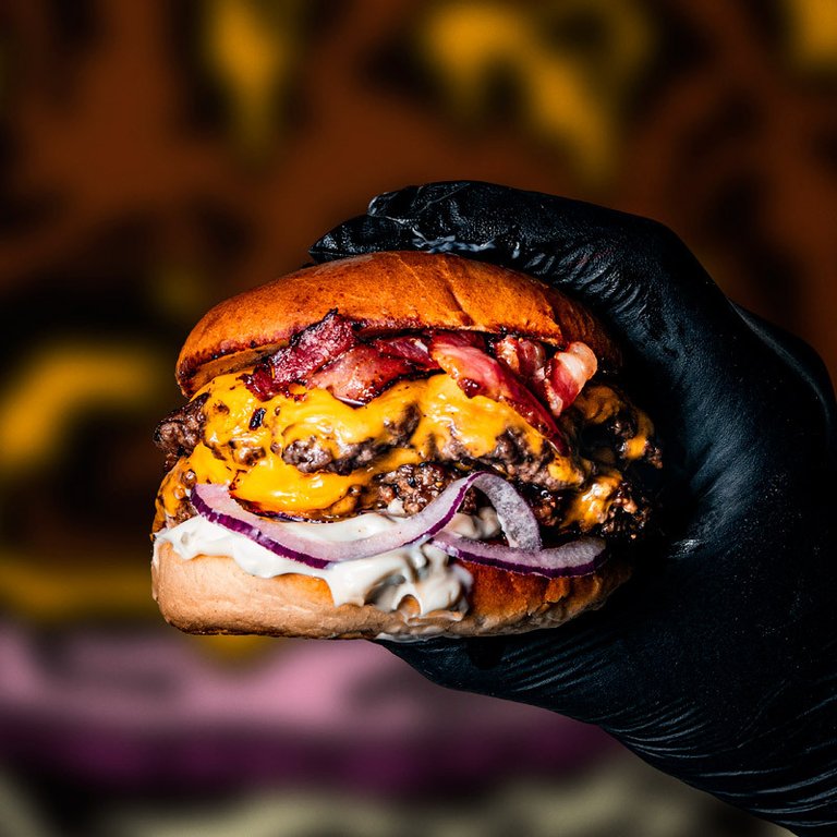Restaurants in Stockholm. A hand holding up a burger with cheese and bacon at Bastard Burgers.