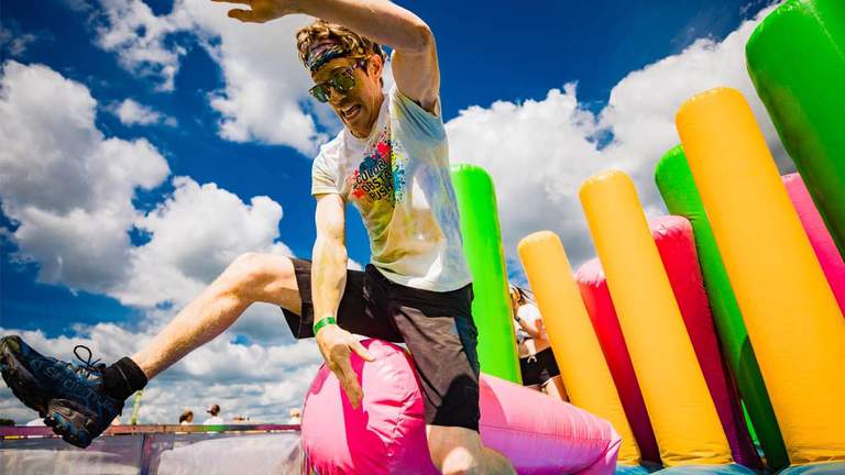 A partisipant of a race jumping over the colorful obstacles.