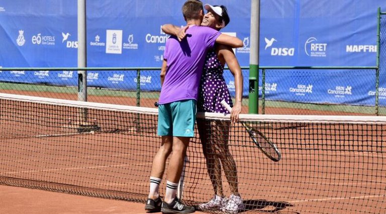 Two tennis players hugging on a tennis court