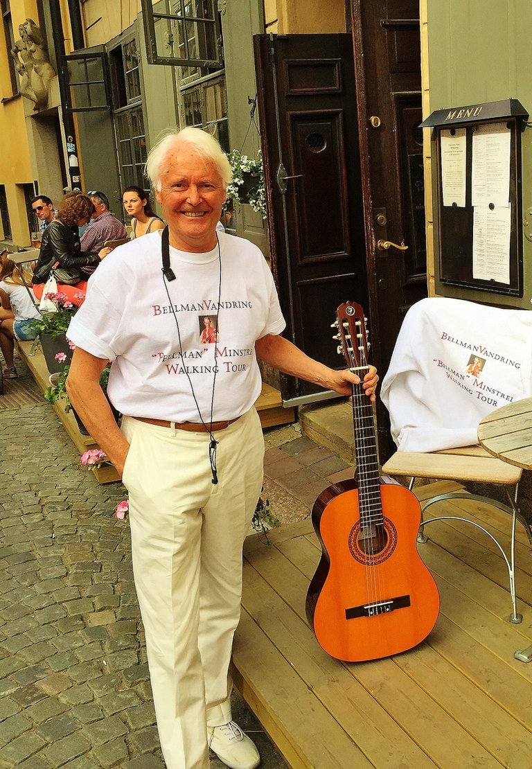 a person standing, smiling and holding a guitar