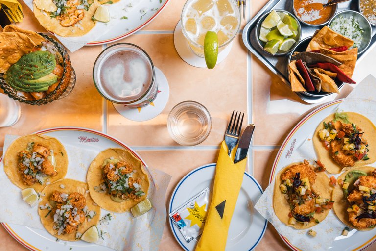 A table set for dinner at MXCO in Stockholm. Various plates of Mexican food like tortilla chips and tacos, and beer.