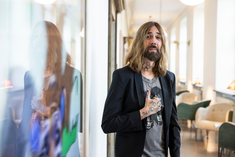 Professor Micael Dahlén at the Stockholm School of Economics. A man with a beard, lång hair and tatoos giving a thumbs up,