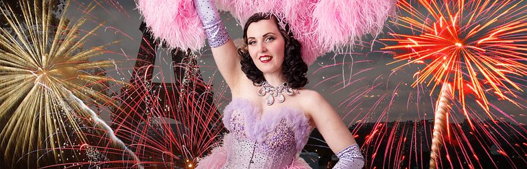 A woman dressed in a glittery dress, against a backdrop of fire works.jo