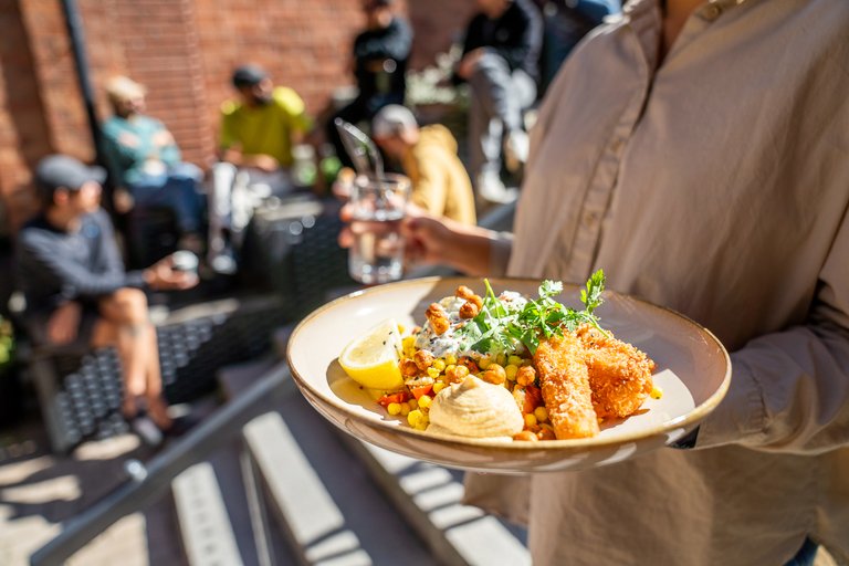 A person holding a plate with food and a glass of water.