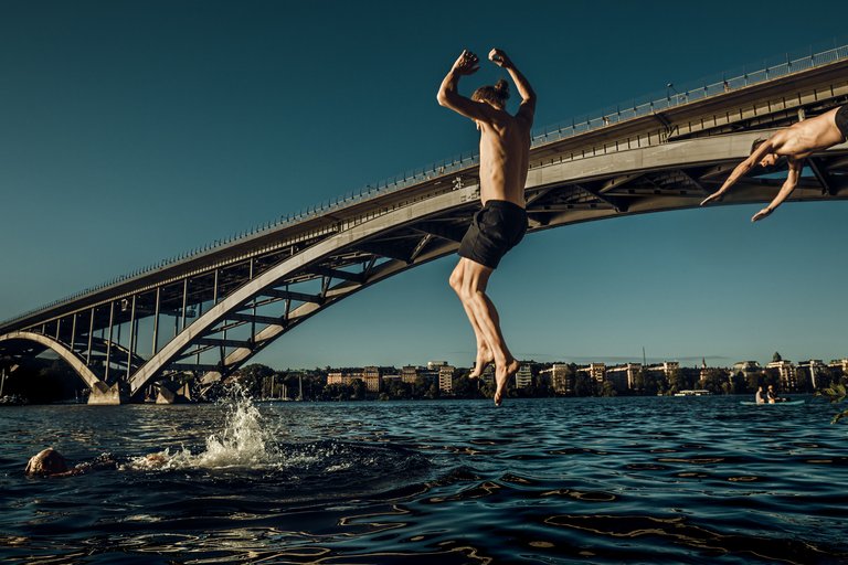 Friends taking a swim and jump into the water of Stockholm