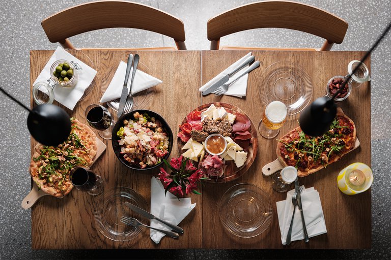 A table with several different dishes, glasses, napkins and cutlery.