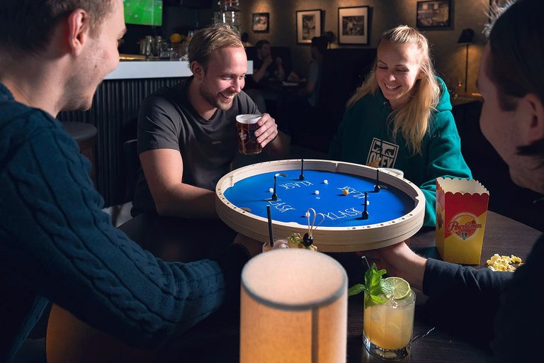 A group of people are playing the boardgame Klask at Birka Bowling in Stockholm.