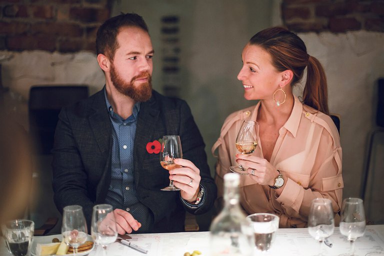 A man and a woman sitting at a table and holding wine glasses