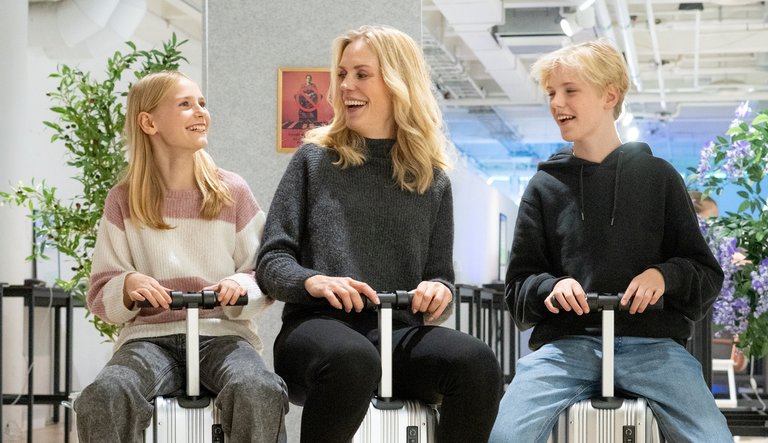 a woman and two children sitting on suitcases