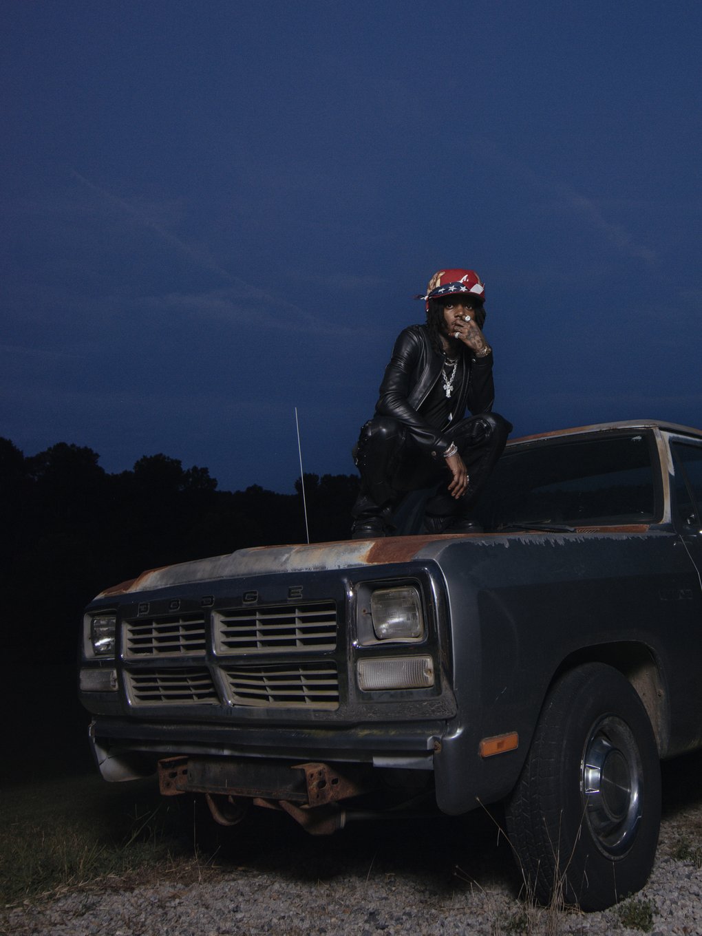 JID posing on the hood of a truck.