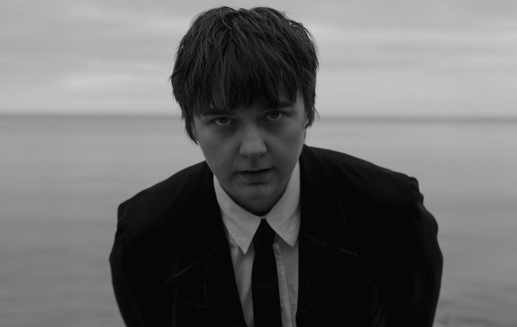 Kerstin Ljungström, standing by the sea, wearing a suit and tie.