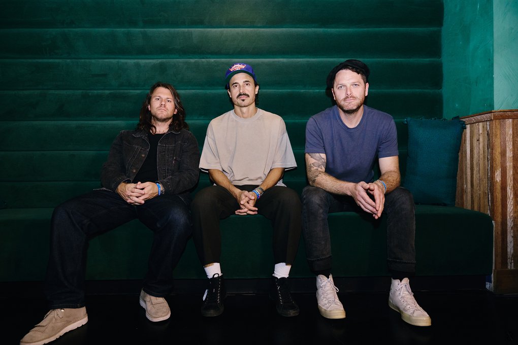 Tre män som sitter i en soffa.