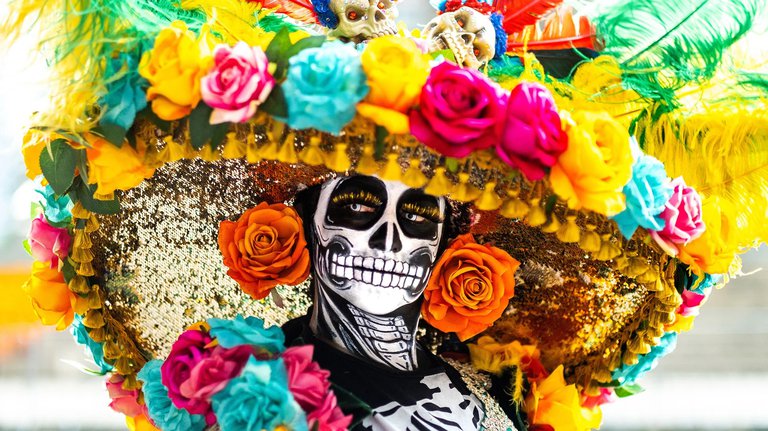 A person in a costume of skeleton and in a hat with flowers.